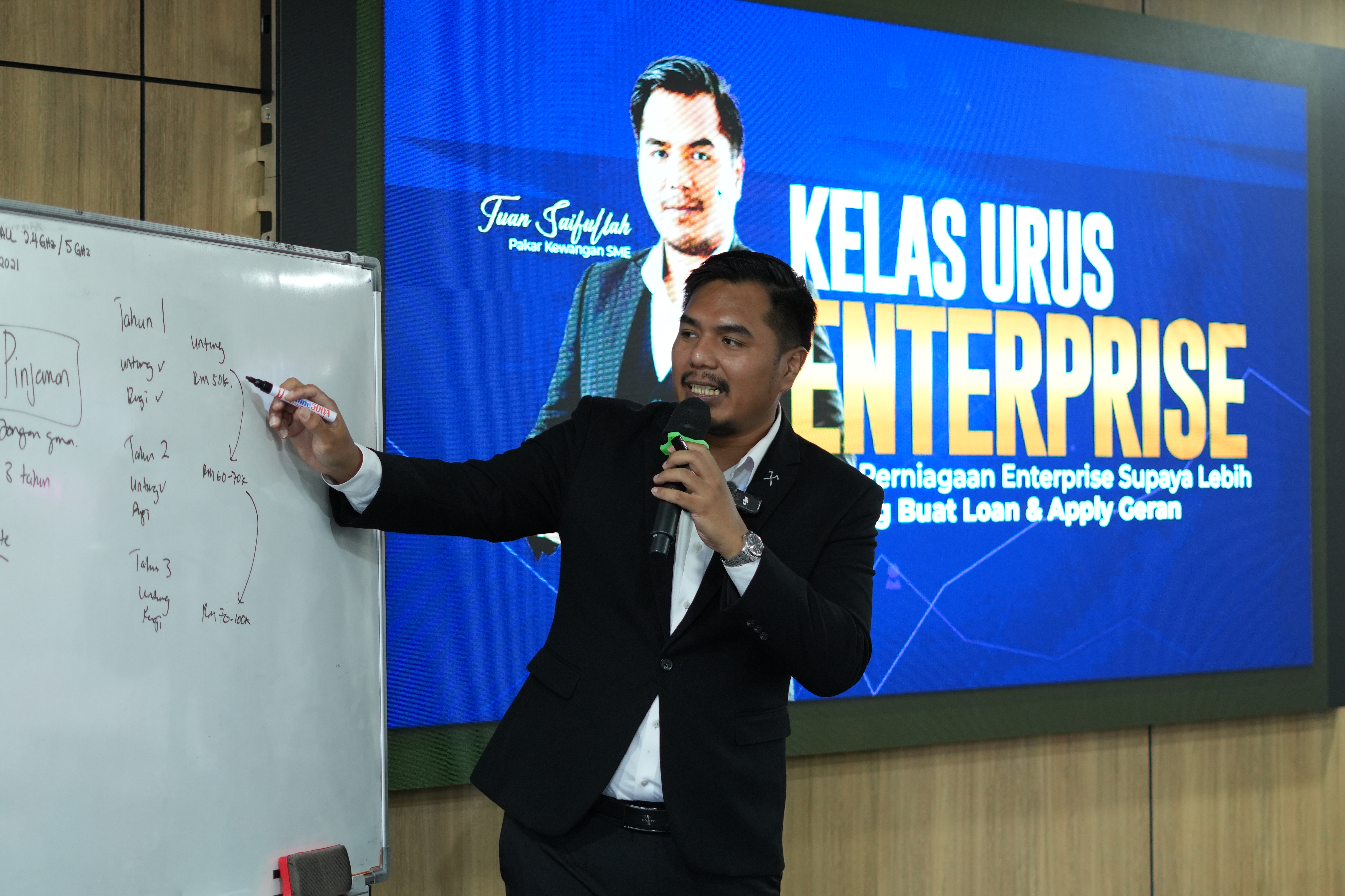 Saifullah menerangkan contoh rekod untung rugi pada papan putih